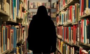 書棚の間を歩く黒い服の人の後ろ姿、2020年9月3日（金）に開催する東京読書交換会vol.111の広報、圧倒的な物量の本が情報にみえる、読書会＠オンライン（記事内挿入画像）